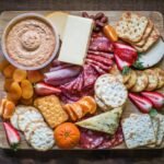 Photo of Healthy Snack options, such as crackers and hummus, cheese, meat, and fruit.