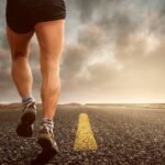 Man wearing sports shoe while walking on asphalt road