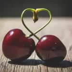 Close up Photo of 2 cherries with heart shaped stem